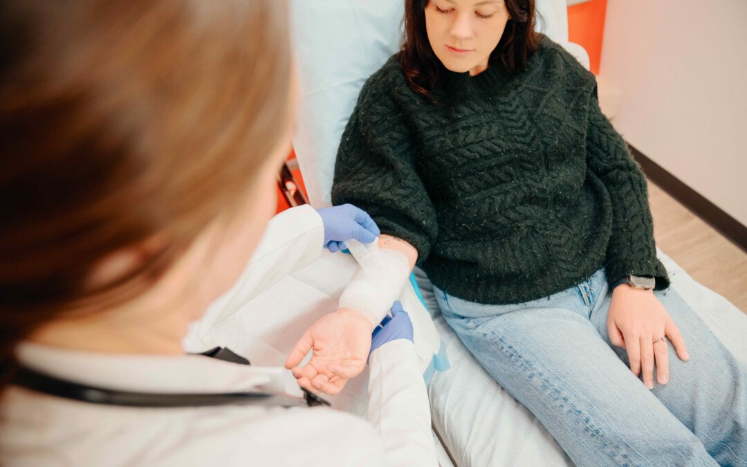 Female patient having right lower arm wrapped in bandaging after getting a rash or burn while gardening by a female AFC healthcare provider in an AFC examination room.